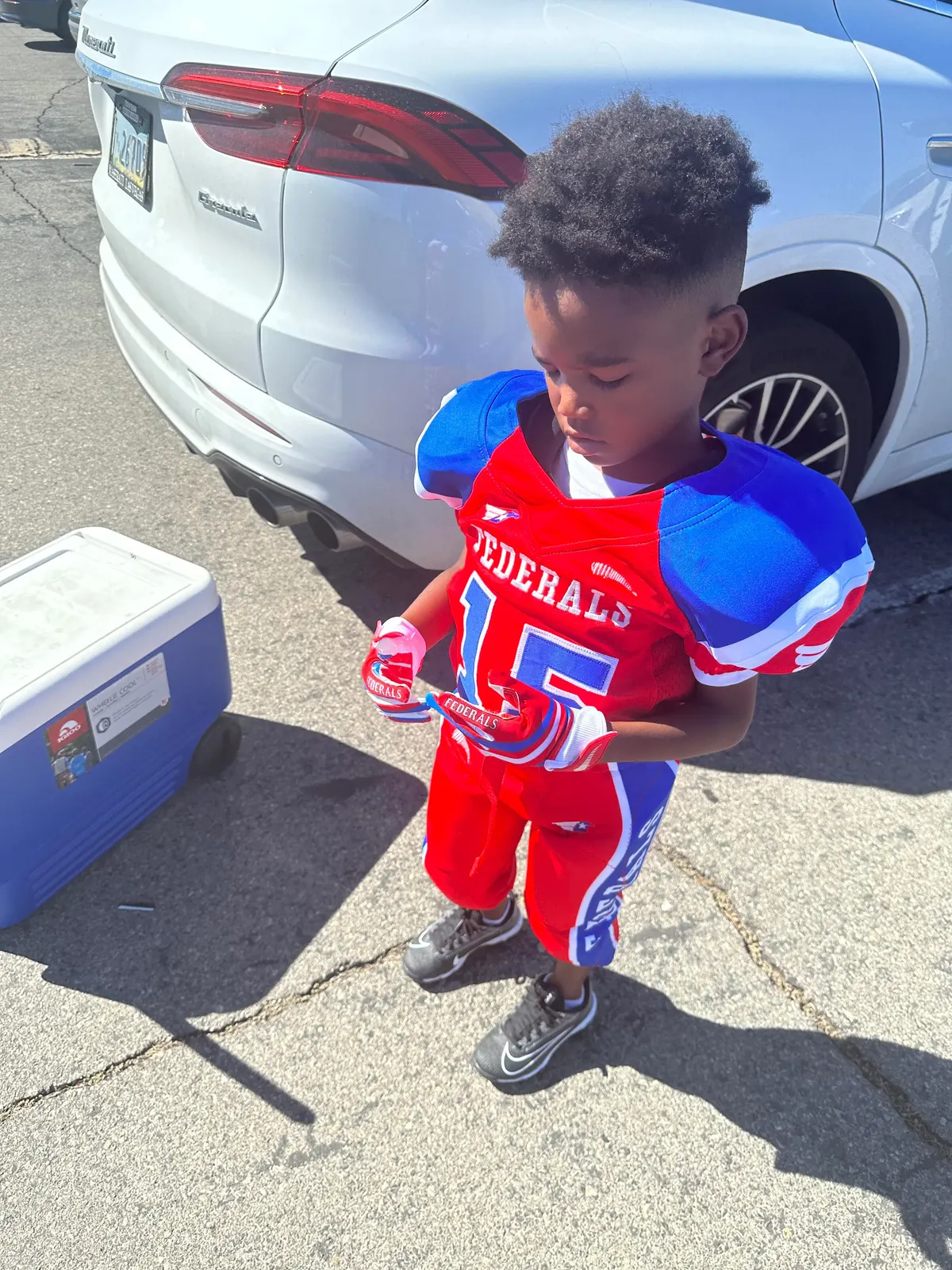 Youth football player in a red, white, and blue Federals uniform outside before a game